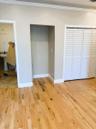 Hardwood flooring, white louvered bifold closet doors, and crown molding