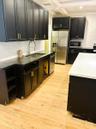 Kitchen featuring matte black cabinetry with gold-tone hardware, wood-finish flooring, quartz countertops, a stainless steel undermount sink with a pu