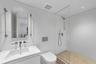 Modern bathroom featuring a floating vanity with a seamless sink, wall-mounted faucets, a wall-hung toilet, and a glass-enclosed shower with stone til