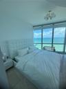 Floor-to-ceiling windows featuring ocean scenery, tile flooring, and a modern multi-globe chandelier