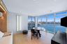 Floor-to-ceiling windows, wood-finish flooring, built-in recessed shelving, integrated lighting, and water-fronting balcony