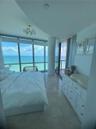 Floor-to-ceiling windows, stone tile flooring, multi-light gold-finish flush mount fixture, and structural cylindrical column