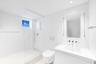 Minimalist bathroom featuring a glass-enclosed shower with a built-in recessed shelf, wall-mounted dual-flush toilet, integrated vanity with a rectang
