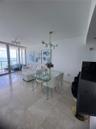Open-concept interior featuring large-format tile flooring, floor-to-ceiling glass sliding doors, and modern multi-arm globe chandeliers