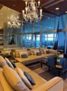 Floor-to-ceiling glass curtain walls, expansive wall-to-wall mirrored paneling, decorative multi-tiered chandelier, and polished dark ceiling finish