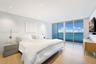 Floor-to-ceiling sliding glass doors, light wood-finish flooring, recessed ceiling lighting, and expansive water and skyline scenery