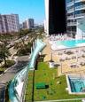 Elevated outdoor terrace featuring a swimming pool, integrated spa, manicured lawn, and glass perimeter railing