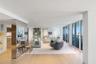 Open-concept living space featuring wood-finish flooring, floor-to-ceiling glass sliding doors, recessed ceiling lighting, and reflective floor-to-cei