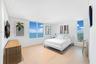 Neutral-toned interior featuring wood-finish flooring, recessed lighting, and expansive floor-to-ceiling windows offering water and landscape vistas