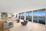 Open-concept living area featuring floor-to-ceiling glass sliding doors, recessed lighting, wood-finish flooring, and a private balcony