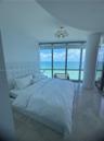 Floor-to-ceiling windows featuring ocean scenery, stone flooring, a structural column, and a multi-globe light fixture