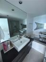 Contemporary bathroom featuring a dark-finish floating vanity, rectangular vessel sink, stone-surround soaking tub, and recessed ceiling lighting