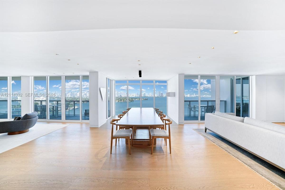 Open-concept living space featuring wood-finish flooring, recessed lighting, and floor-to-ceiling windows with expansive water and city skyline outloo