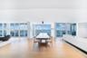 Open-concept living space featuring wood-finish flooring, recessed lighting, and floor-to-ceiling windows with expansive water and city skyline outloo