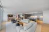Open-concept main living area featuring light wood-finish flooring, recessed lighting, floor-to-ceiling glass sliding doors, and a chef-inspired kitch