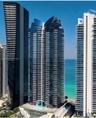High-rise architectural exterior featuring glass-curtain facade, wrap-around balconies, and coastal frontage