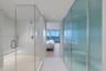 Enclosed shower with built-in bench, frameless glass door, ribbed glass privacy panel, and recessed lighting