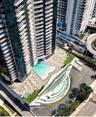 High-rise architectural exterior featuring tiered glass balconies, an expansive multilevel swimming pool area, multi-level terrace decks, and landscap