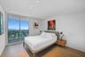 Floor-to-ceiling glass sliding doors, wood-finish flooring, recessed ceiling lighting, and a private balcony