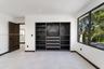 Built-in dark-toned cabinetry with integrated shelving and drawers, large-format tile flooring, recessed lighting, and expansive window with dark meta