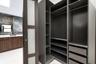 Custom built-in dark finish closet shelving with integrated drawers and hanging rods, featuring a sliding door with frosted glass panels, wood-finish 
