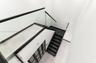 Staircase featuring dark-toned treads, glass railings with black metal trim, and a multi-panel door with frosted glass inserts