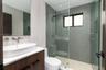 Bathroom featuring a wood-finish vanity with a white vessel sink, wall-mounted faucet, frameless glass-enclosed shower with textured wall tile, and re