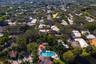 Aerial perspective highlighting a mature residential neighborhood featuring abundant tree canopy and a community recreation area with a swimming pool 