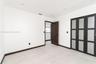 Interior space featuring light-toned tile flooring, recessed ceiling lighting, a dark-finish interior door, and a built-in closet with frosted glass p