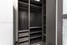 Custom storage system featuring dark wood-finish cabinetry, integrated shelving, tiered drawer units, and metal garment rods