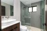 Modern bathroom featuring a wood-finish floating vanity with a white vessel sink, quartz countertop, wall-mounted faucet, and a glass-enclosed shower 