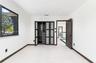 Room featuring large-format tile flooring, built-in wardrobe with frosted glass panel doors, dark-toned interior door, and multi-pane window