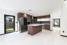 Kitchen featuring flat-panel wood-finish cabinetry, a central island with a solid-surface countertop, integrated stainless steel appliances, dark ston