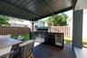 Covered patio featuring a wood-finish deck and an outdoor kitchen equipped with a stainless steel grill and a built-in beverage refrigerator, enclosed