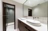 Floating vanity featuring a dual-sink countertop, vessel sinks, wall-mounted faucets, large frameless mirror, and a walk-in shower with glass enclosur