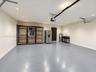 Garage space featuring an epoxy-coated floor, recessed lighting, a utility sink, and a stainless steel refrigerator