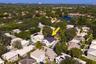 Aerial perspective featuring a two-story residence with a dark shingle roof, integrated pool, and mature canopy trees on a landscaped lot