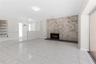 Floor-to-ceiling stone fireplace surround, tile flooring, glass-paneled room divider, sliding glass door, and flush-mount lighting