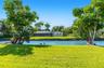 Waterfront lot featuring a manicured lawn, mature trees, and a screen-enclosed patio