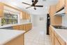 Kitchen featuring light-finish cabinetry, white solid-surface countertops, tile flooring, recessed lighting, and a ceiling fan