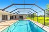 Screen-enclosed pool deck featuring tile flooring, a rectangular swimming pool, and multiple sliding glass door access points