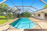 Screen-enclosed pool featuring a tile-surrounded deck, built-in ceiling fans, and a spacious grass yard
