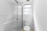 Shower enclosure with textured glass sliding doors, white ceramic toilet, and a window with frosted glass