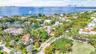 Aerial perspective of waterfront property featuring mature landscaping, paved driveway, and proximity to open water
