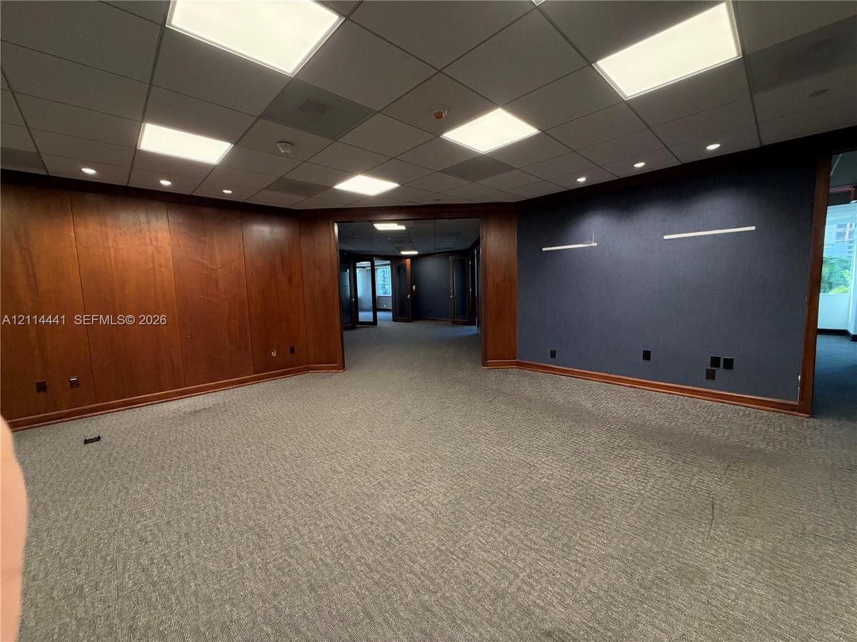 Wood-paneled wall accents, suspended grid ceiling with recessed lighting, and textured wall finish