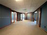Interior space featuring wood-frame glass-panel doors, neutral carpeting, and a drop-tile ceiling