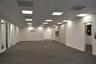 Open-concept floor plan featuring a grid ceiling with recessed panel lighting, neutral carpeting, built-in cabinetry, and glass-paneled interior doors