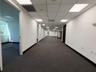 Hallway featuring charcoal carpeting, white walls, recessed panel ceiling, and multiple doorway entries