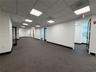 Open interior space featuring commercial-grade carpeting, recessed grid ceiling with integrated lighting, and multiple wood-trimmed glass panel doors