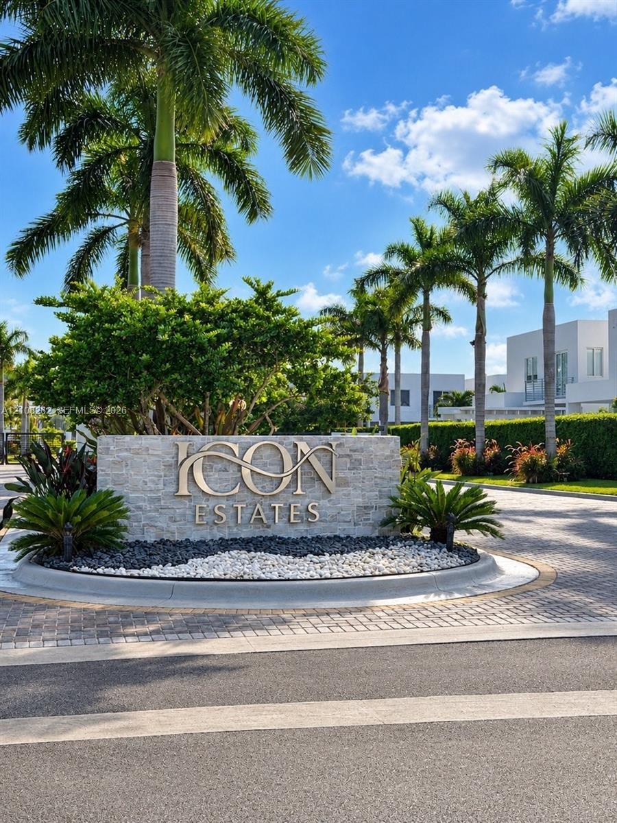 Stone-clad monument signage featuring metal lettering, surrounded by professional landscaping, palm trees, and a paved circular driveway